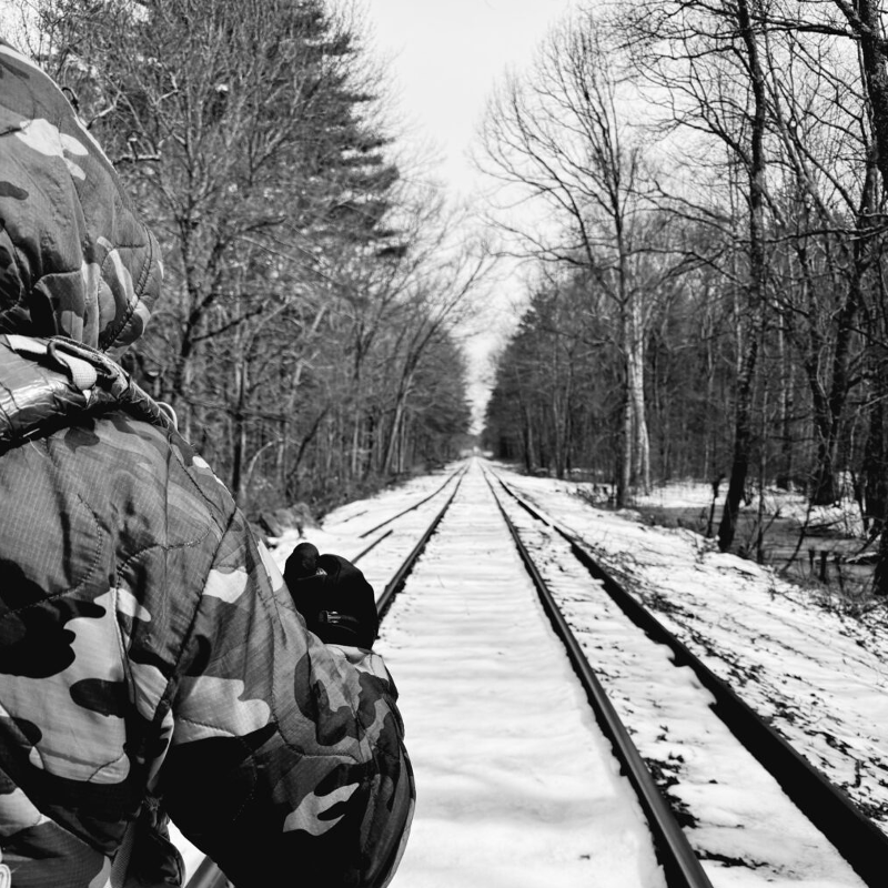 person walking down railroad tracks covered in snow